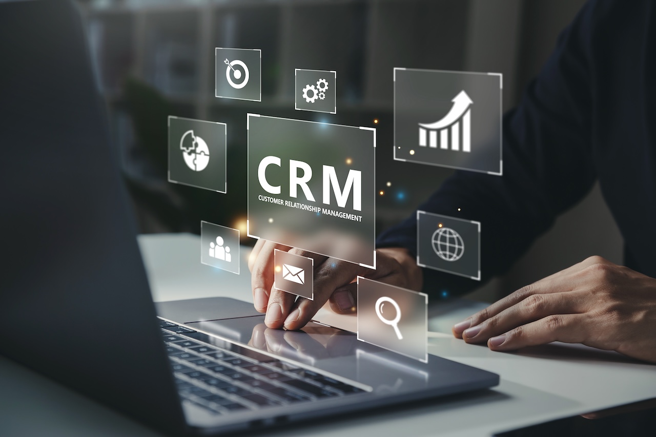 Businessman using laptop with CRM icon on virtual screen.